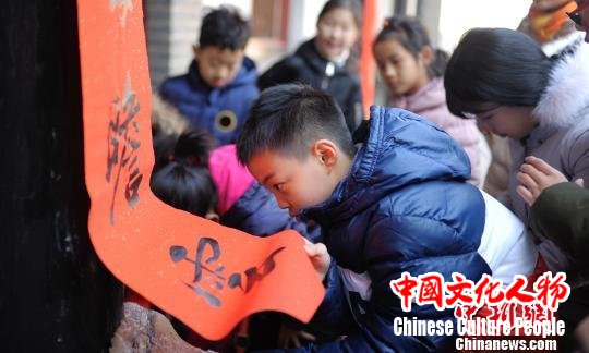 “孔府过大年”系列活动中设置了游客参与贴春联的环节。图为参与活动的小游客帮忙贴春联。　陈硕 摄