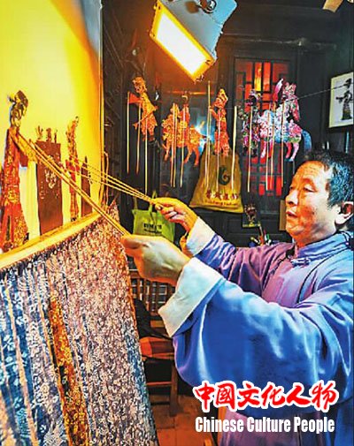 山东台儿庄古城非遗文化展示区，现年60岁的国家级非物质文化遗产鲁南皮影戏传承人陈守科正在向游客表演皮影戏，让游客们感受传统文化的魅力。高启民摄