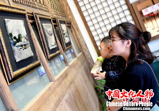 由泉州锡雕工艺师林慧创作的锡雕艺术作品《印象泉州》吸引一对母子观看。　记者刘可耕 摄
