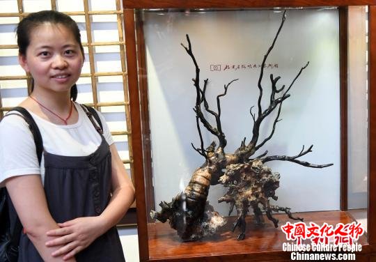 一名年轻女观众与参展海柳雕艺术精品合影。　记者刘可耕 摄