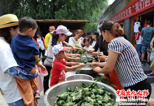 文化苑工作人员摆好包粽子的苇叶、糯米等，和游客一同包粽子。　韩冰 摄