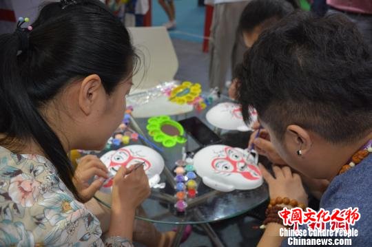 观展者体验脸谱制作教学。　韩成功 摄