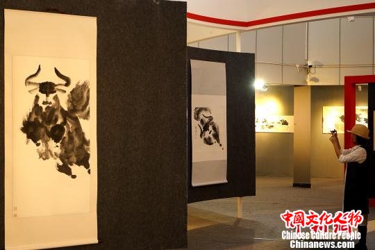 6月19日，一位观众在拉萨参观孟繁华水墨大写意牦牛个人画展，用手机拍摄绘画作品。　江飞波 摄